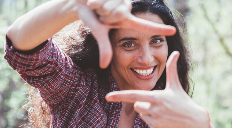 a woman holding her hands in front of her face in the shape of a frame